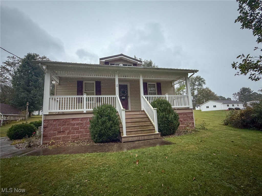 Bungalow featuring covered porch and a front lawn