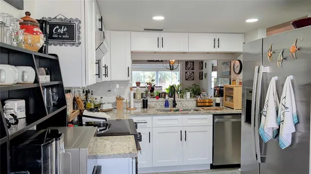 a kitchen with stainless steel appliances kitchen island granite countertop a refrigerator and a sink
