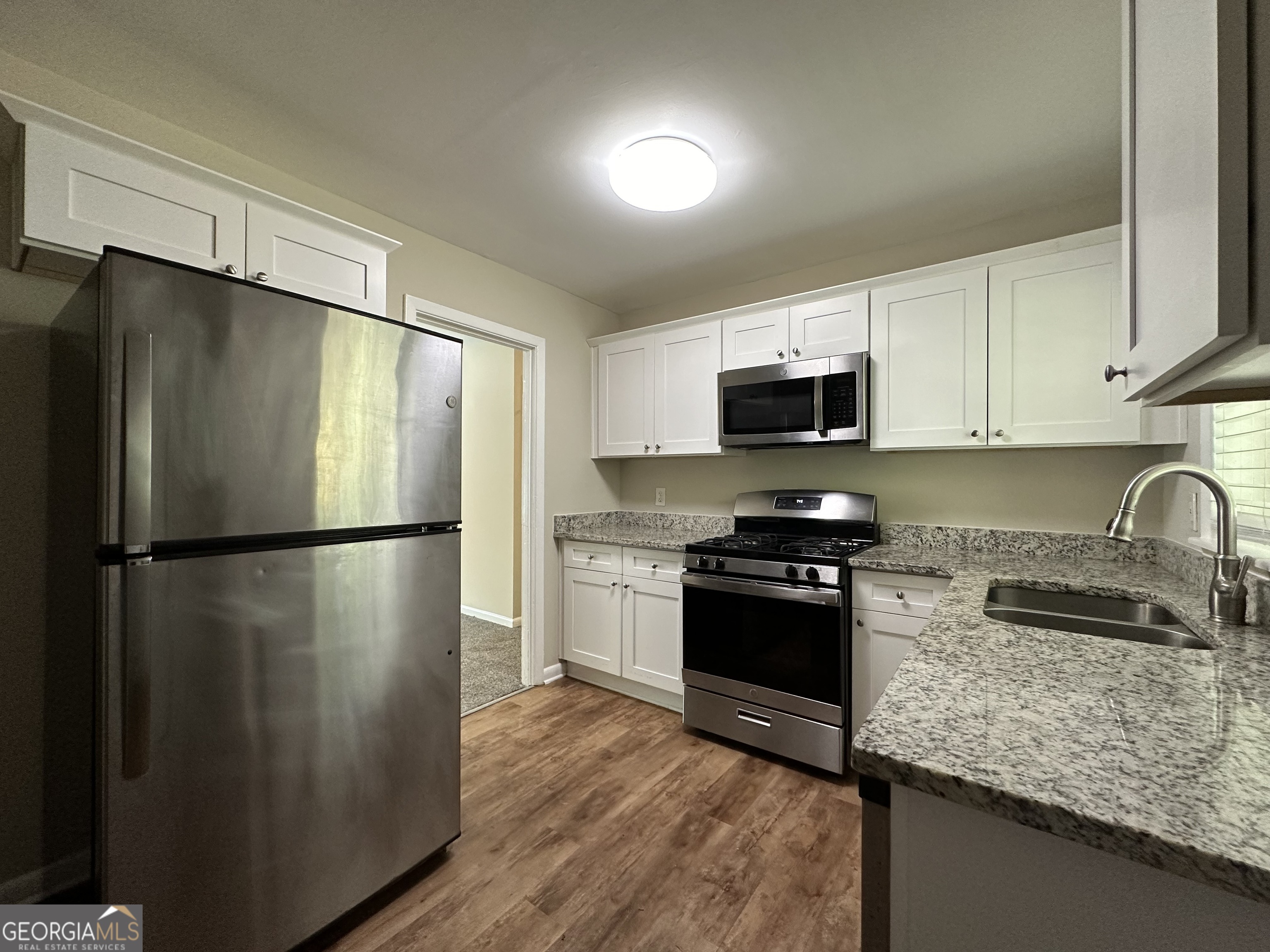 1154 Penn Court Southeast Atlanta, GA 30315 - Photo 4 of 9 a kitchen with granite countertop a refrigerator stove and microwave