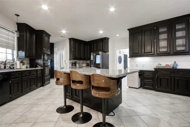a kitchen with granite countertop a stove top oven a sink a dining table and chairs