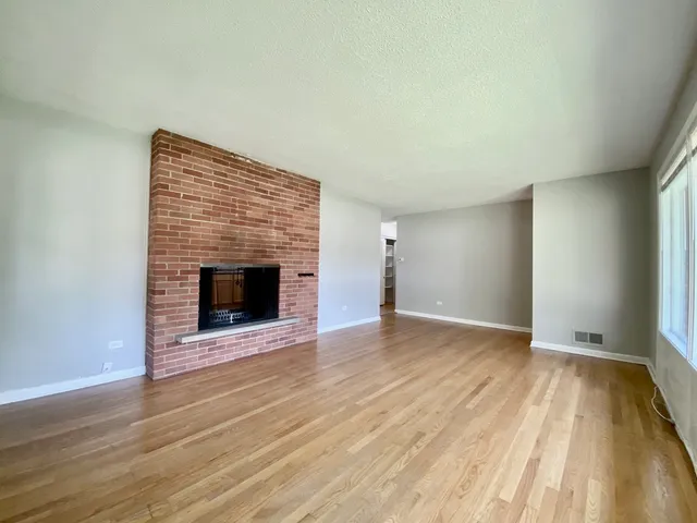a view of empty room with wooden floor and fireplace
