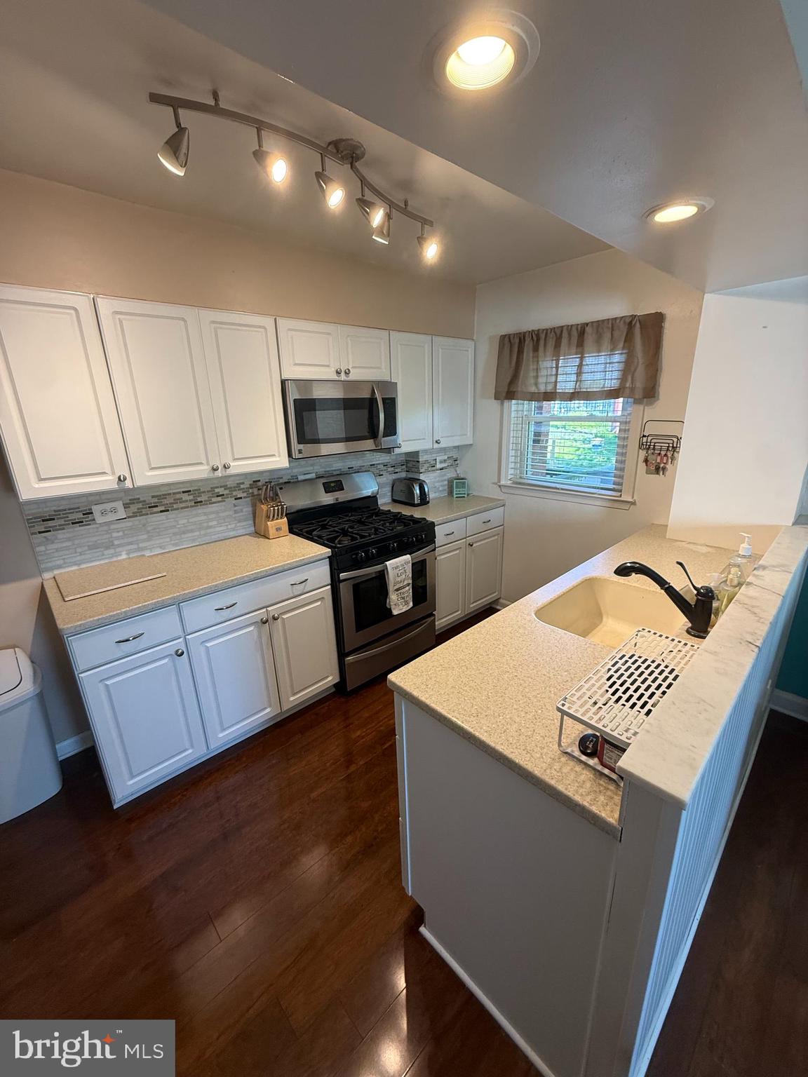 2235 Hawthorne Road Baltimore, MD 21220 - Photo 10 of 35 a kitchen with stainless steel appliances kitchen island granite countertop a refrigerator a sink dishwasher a stove and white cabinets with wooden floor