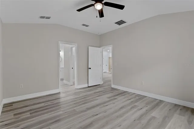 an empty room with wooden floor closet and ceiling fan