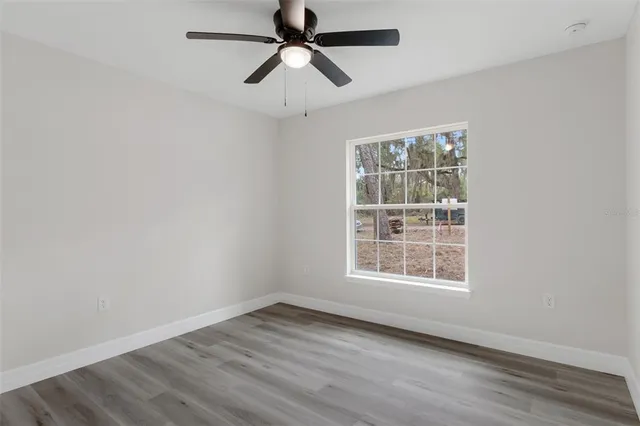 an empty room with wooden floor chandelier fan and closet area