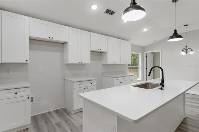 a view of kitchen with kitchen island wooden floor stainless steel appliances and cabinets