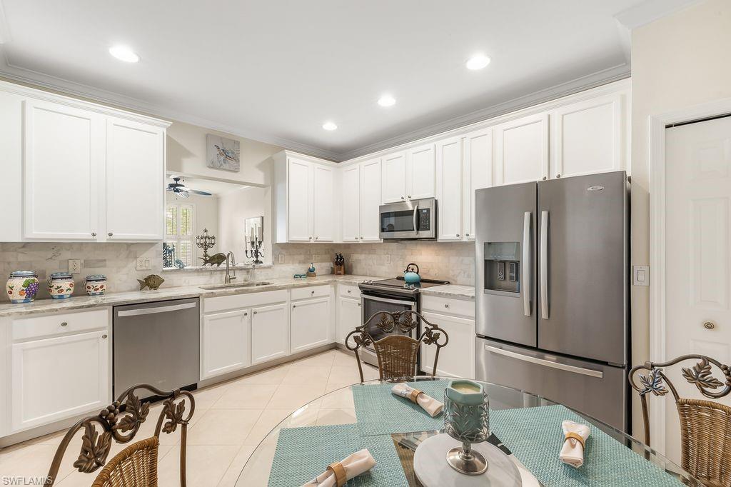 3951 Cherrybrook Loop Fort Myers, FL 33966 - Photo 3 of 34 a kitchen with stainless steel appliances granite countertop a sink a stove a refrigerator cabinets and chairs
