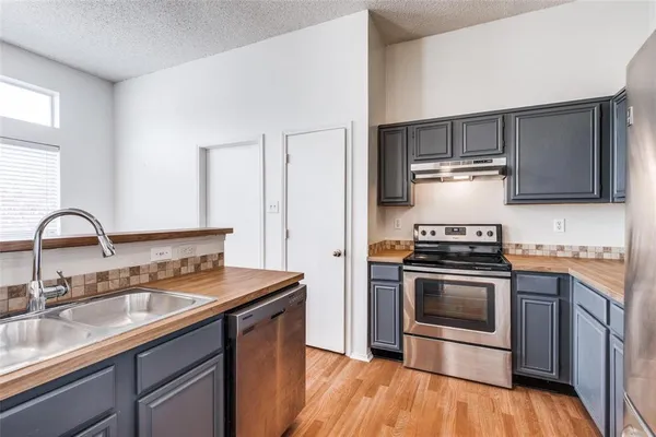 a kitchen with stainless steel appliances granite countertop a stove a sink and a microwave