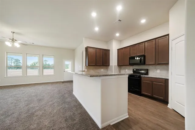 a kitchen with stainless steel appliances granite countertop a stove top oven a sink dishwasher a refrigerator and a microwave oven with wooden floor