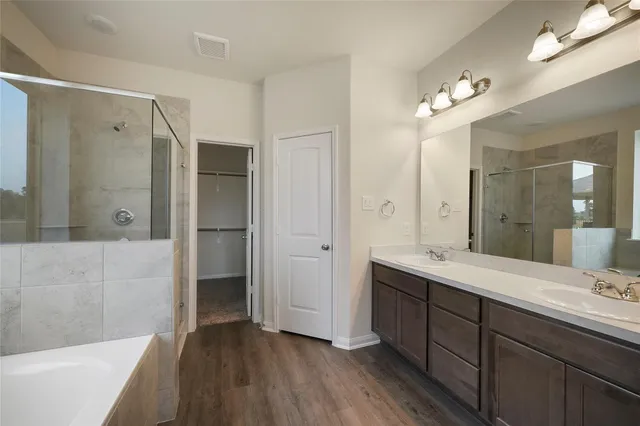 a spacious bathroom with a double vanity sink a large mirror and shower