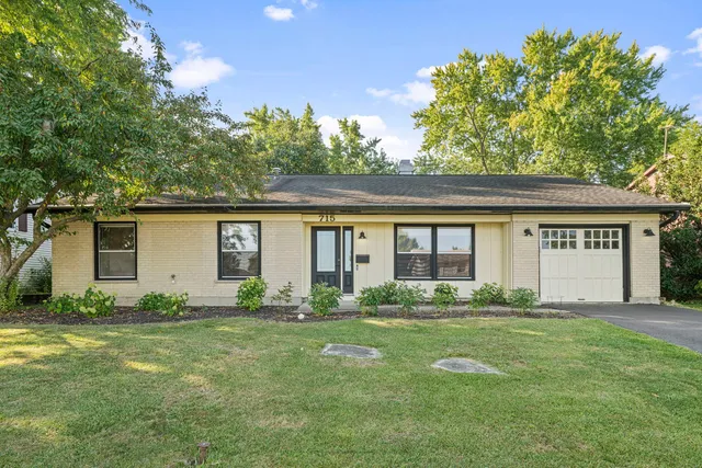 a front view of house with yard and trees in the background