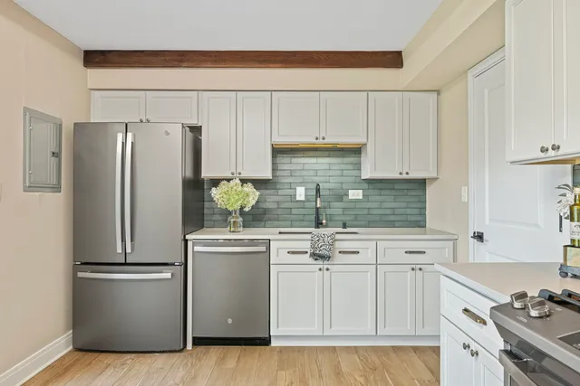 a kitchen with stainless steel appliances a refrigerator a sink and white cabinets