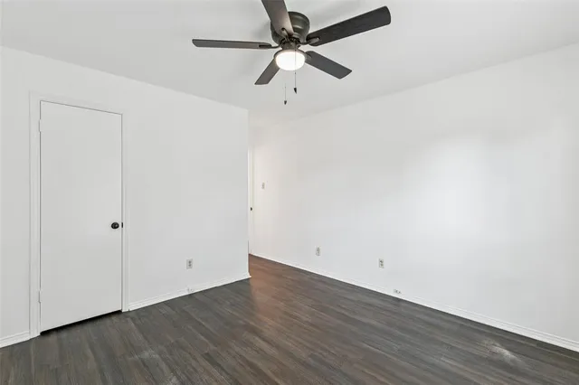 an empty room with wooden floor and ceiling fan