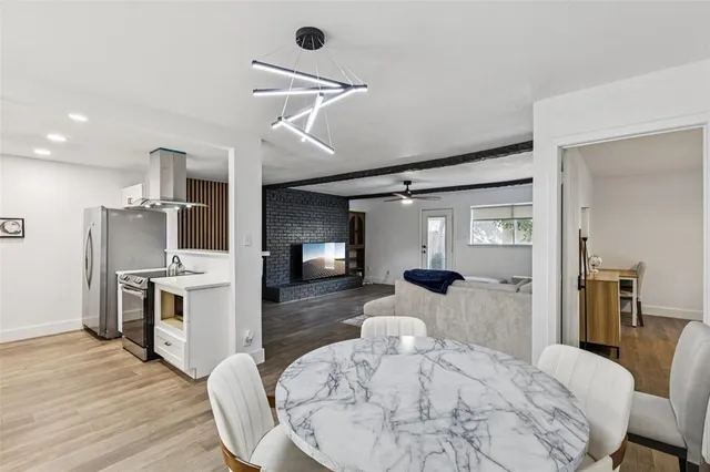 a kitchen with stainless steel appliances kitchen island granite countertop a stove a sink a refrigerator and a dining table with wooden floor