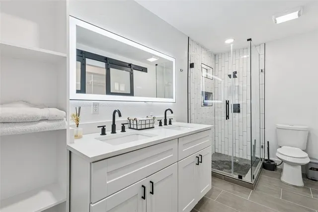 a bathroom with a double vanity sink toilet and shower