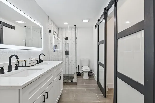 a bathroom with a double vanity sink mirror double shower and a toilet