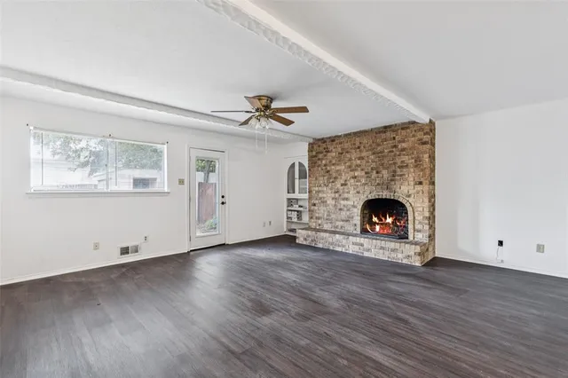 an empty room with wooden floor a fireplace and windows
