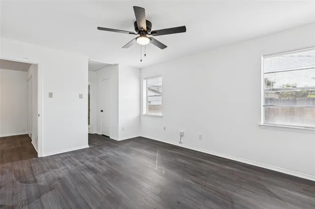 an empty room with wooden floor fan and windows