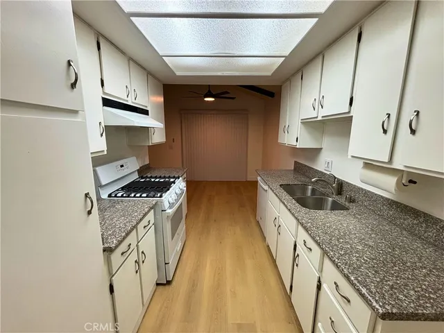 a kitchen with granite countertop a sink a stove and refrigerator