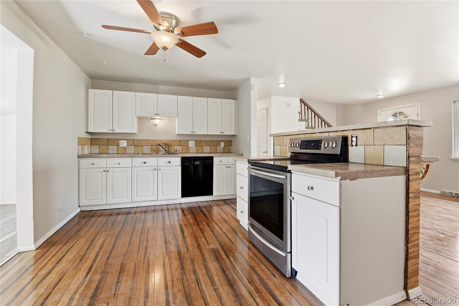 7461 Webster Street Arvada, CO 80003 - Photo 7 of 31 a kitchen with cabinets stainless steel appliances and wooden floor