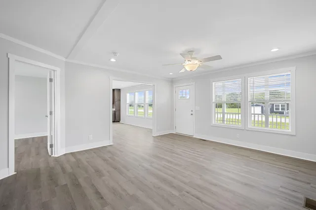 a view of an empty room with a window and wooden floor