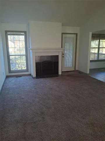 an empty room with windows and fireplace