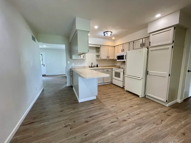 a kitchen with a refrigerator a sink and dishwasher with wooden floor