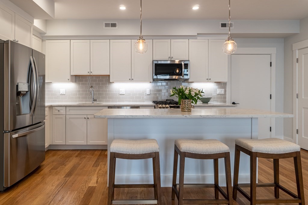 874 South Street, Unit 5 Boston, MA 02131 - Photo 2 of 19 a kitchen with stainless steel appliances a dining table chairs microwave and cabinets