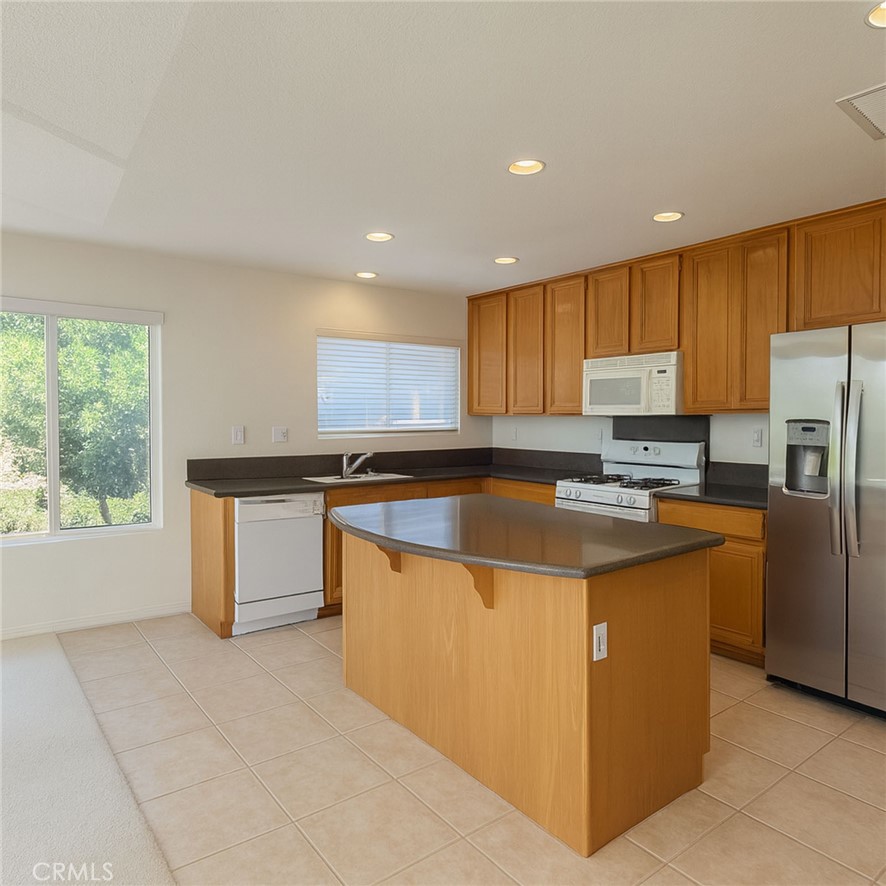 25768 Perlman Place, Unit A Stevenson Ranch, CA 91381 - Photo 9 of 20 a kitchen with stainless steel appliances granite countertop a stove a sink a refrigerator and a microwave