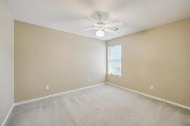 an empty room with a window and a fan