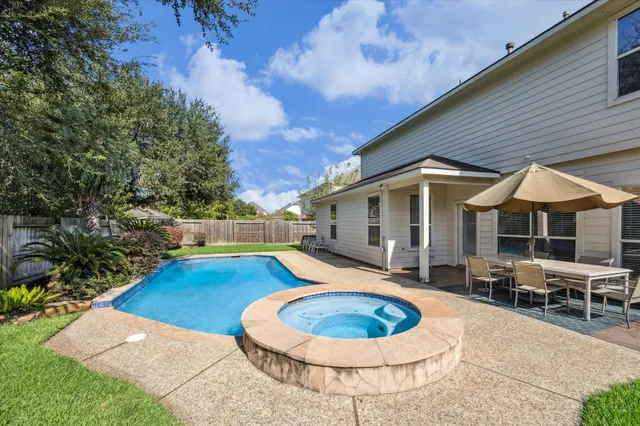 a blue swimming pool with patio outdoor seating and yard