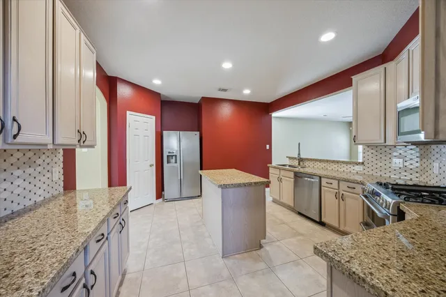 a large kitchen with stainless steel appliances granite countertop a sink and a refrigerator