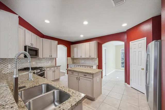 a kitchen with stainless steel appliances granite countertop a stove a sink and a refrigerator