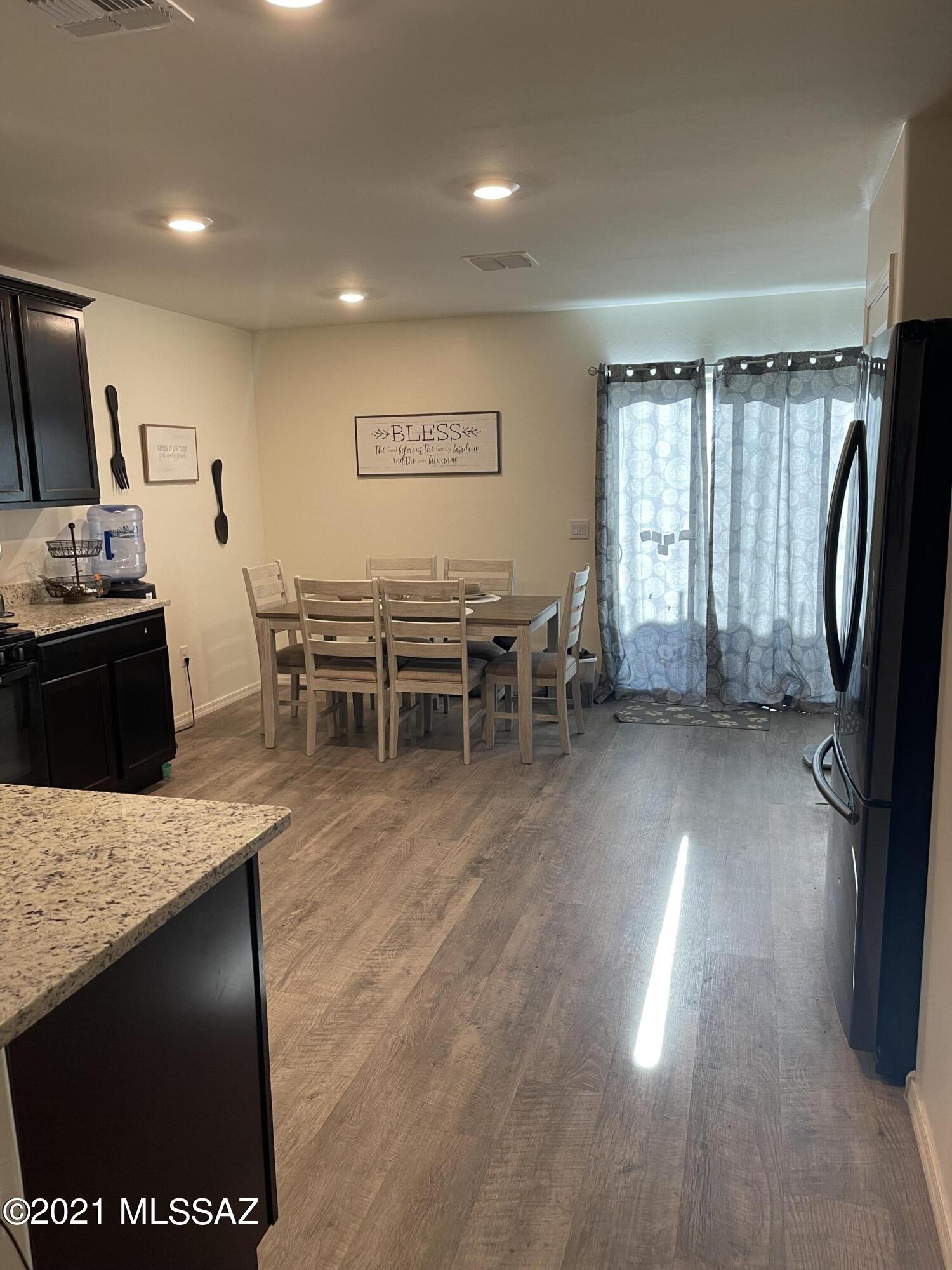 5992 South Antrim Loop Tucson, AZ 85706 - Photo 5 of 15 a open kitchen with stainless steel appliances granite countertop a refrigerator a stove a sink a dining table and chairs with wooden floor