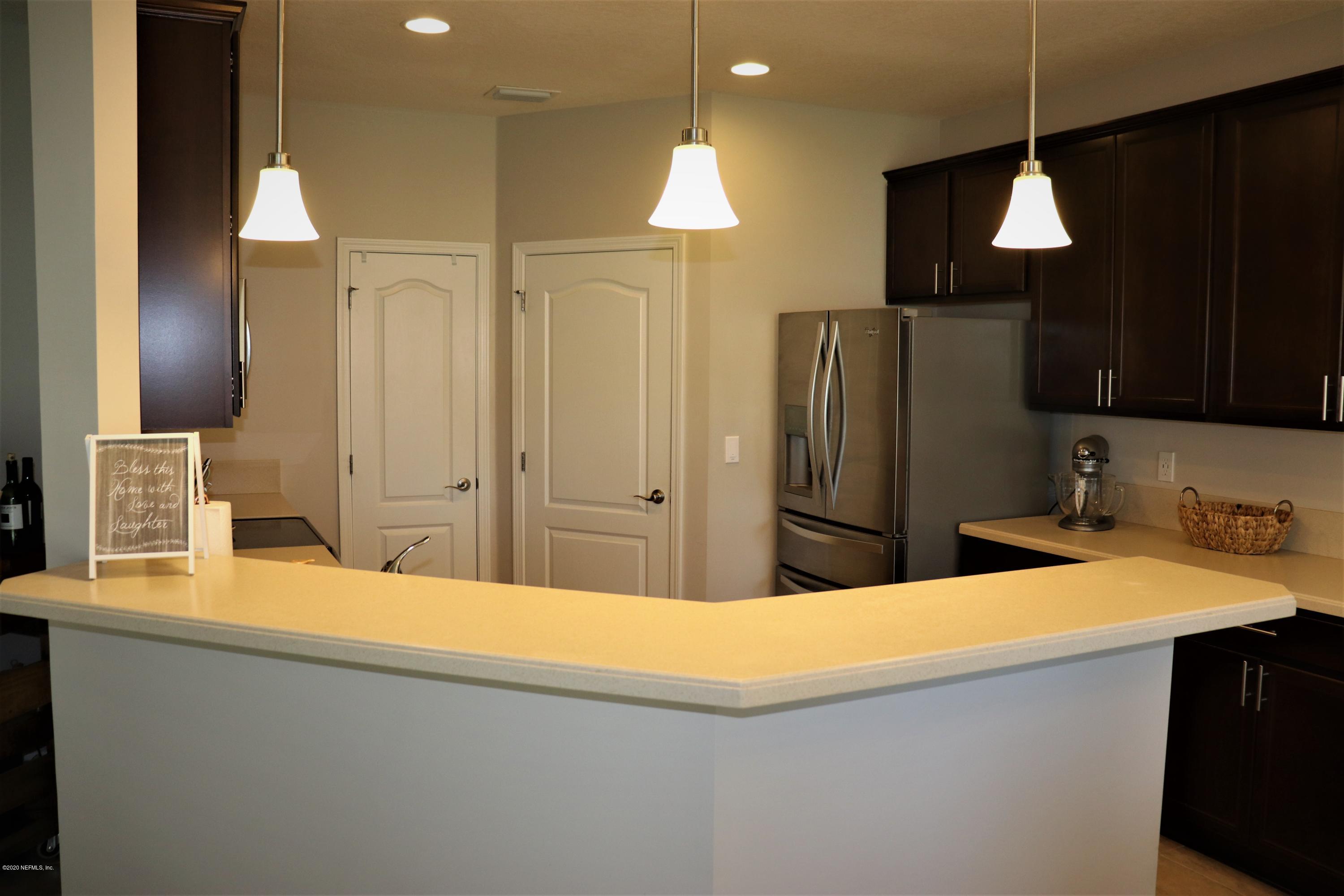 12294 Rouen Cove Drive Jacksonville, FL 32226 - Photo 22 of 41 a kitchen with stainless steel appliances kitchen island a refrigerator sink and wooden cabinets
