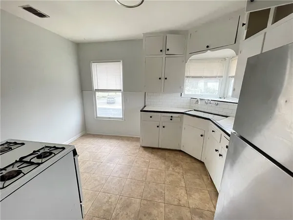 a kitchen with granite countertop a refrigerator a sink a stove and white cabinets