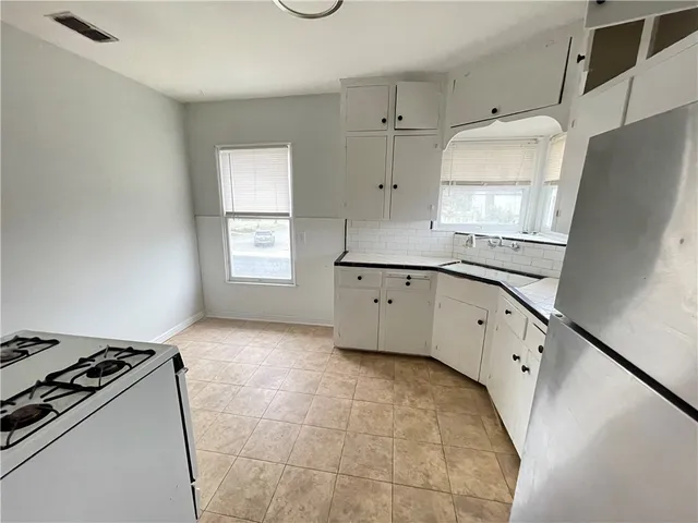 a kitchen with granite countertop a refrigerator a sink a stove and white cabinets