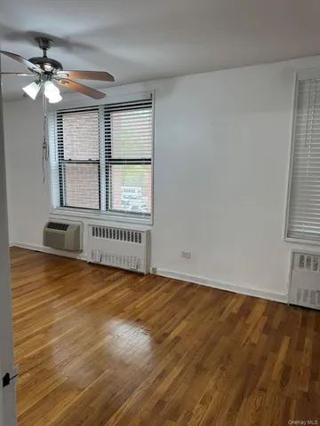 a view of an empty room with a window and wooden floor