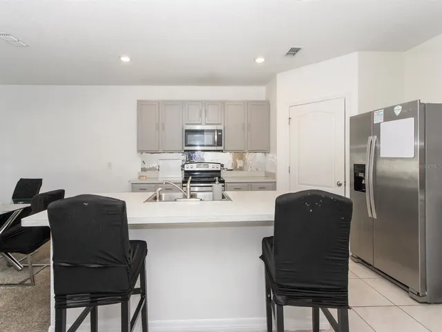 a large white kitchen with kitchen island a counter top space a sink and cabinets