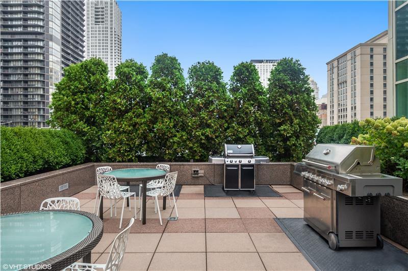 33 West Ontario Street, Unit 40D Chicago, IL 60654 - Photo 22 of 32 a view of a patio with table and chairs potted plants with wooden fence
