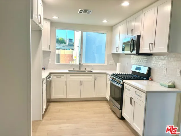a kitchen with white cabinets sink and stainless steel appliances