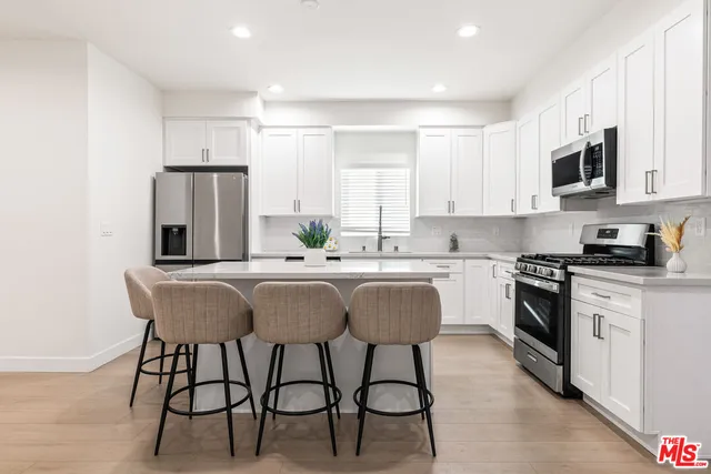 a kitchen with stainless steel appliances granite countertop a table chairs microwave and sink