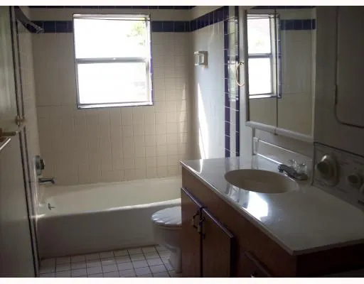 a bathroom with a granite countertop sink a bathtub and window