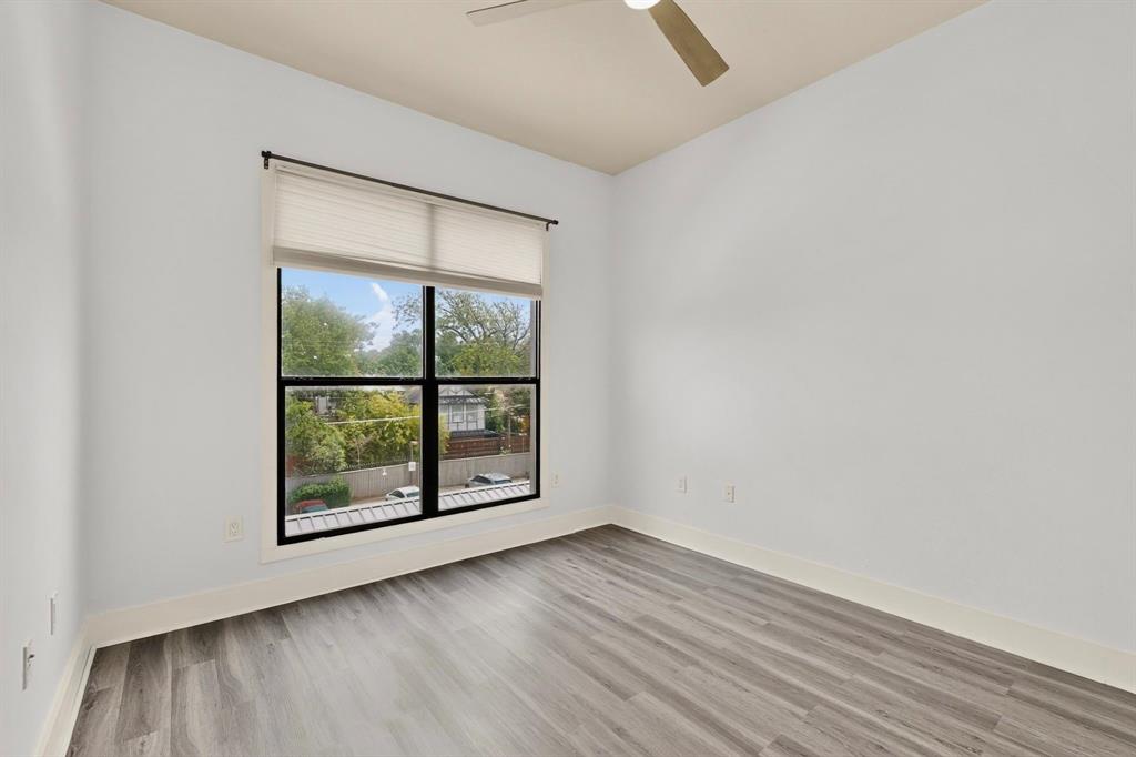 4414 Cedar Springs Road, Unit 318 Dallas, TX 75219 - Photo 21 of 40 Spacious room featuring wood-finish flooring, white baseboards, and bright white walls