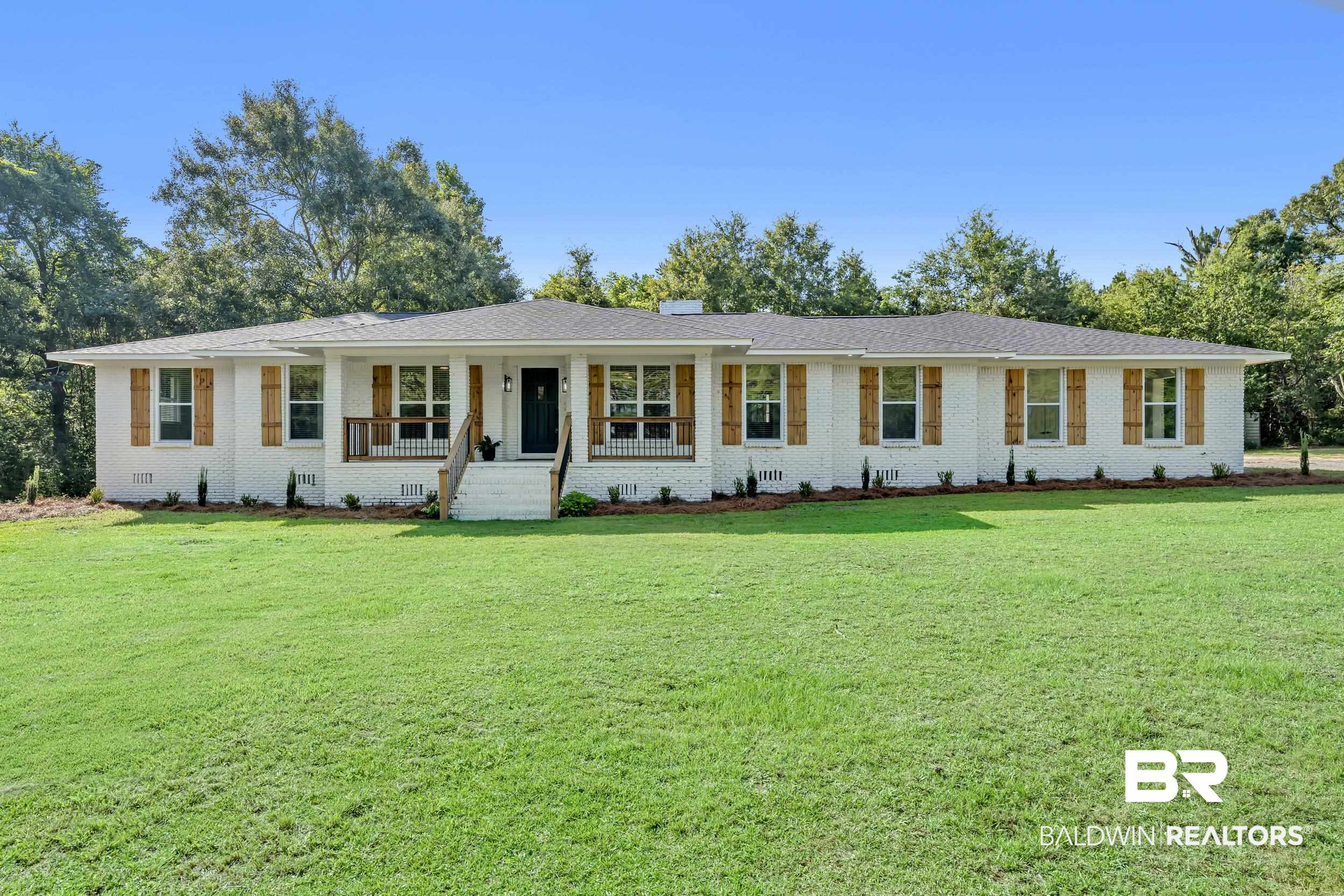 8170 Wilmer Georgetown Road Wilmer, AL 36587 - Photo 1 of 31 White painted brick exterior with a front porch, dark gray shingle roof, and natural wood shutters