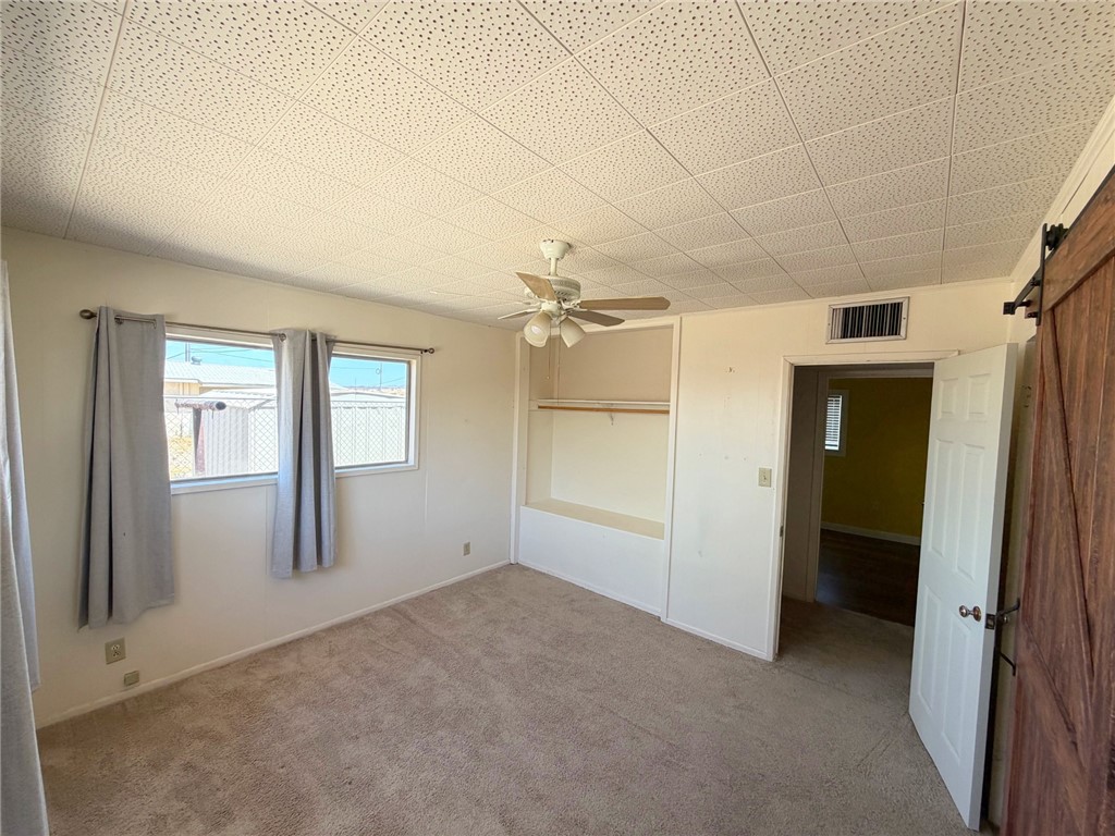 15691 Apache Loop Ehrenberg, AZ 85334 - Photo 13 of 24 Carpeted room with two windows, a ceiling fan, and a built-in closet with shelving