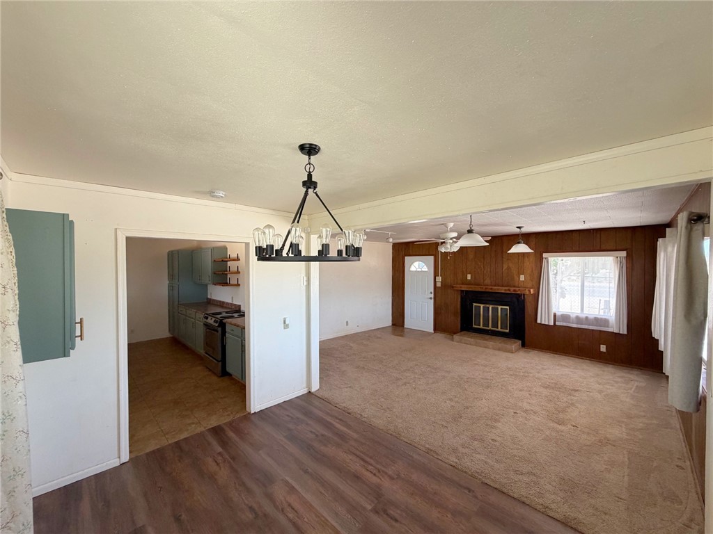 15691 Apache Loop Ehrenberg, AZ 85334 - Photo 4 of 24 Open concept living area featuring a modern chandelier, wood-finish flooring, and a fireplace with a stone hearth