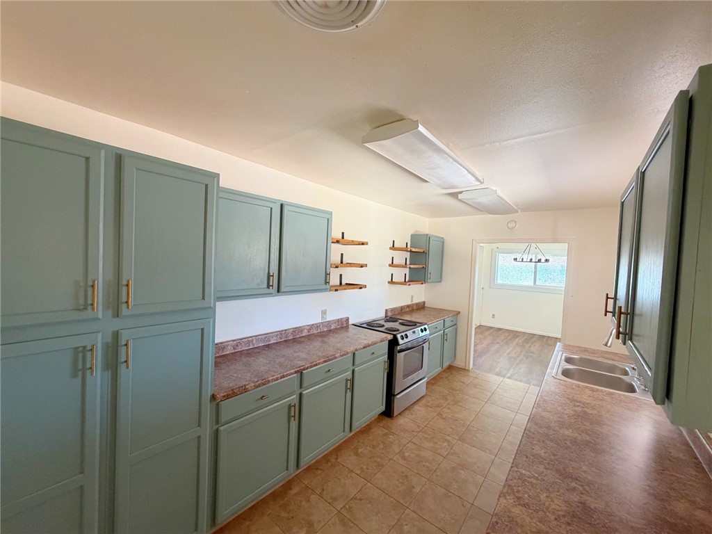 15691 Apache Loop Ehrenberg, AZ 85334 - Photo 9 of 24 Kitchen featuring teal cabinetry, stainless steel range, and a double basin sink