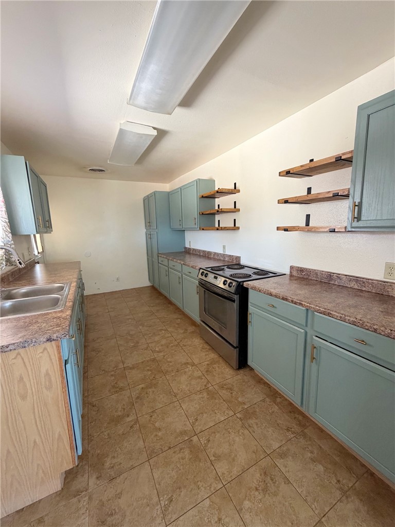 15691 Apache Loop Ehrenberg, AZ 85334 - Photo 10 of 24 Kitchen featuring blue painted cabinetry, wood-finish open shelving, stainless steel range, laminate countertops, and tile flooring