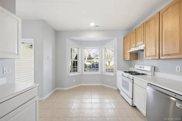 a kitchen with stainless steel appliances granite countertop a stove a sink and a white cabinets