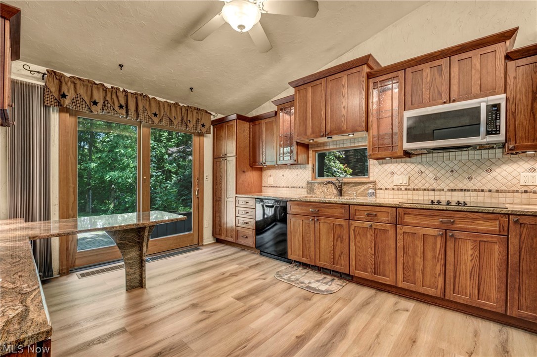 6845 Liberty Road Solon, OH 44139 - Photo 12 of 47 Kitchen featuring wood-finish flooring, ample wood cabinetry, granite countertops, a tiled backsplash, and a sliding glass door